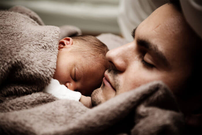 Photo of a father and young baby sleeping
